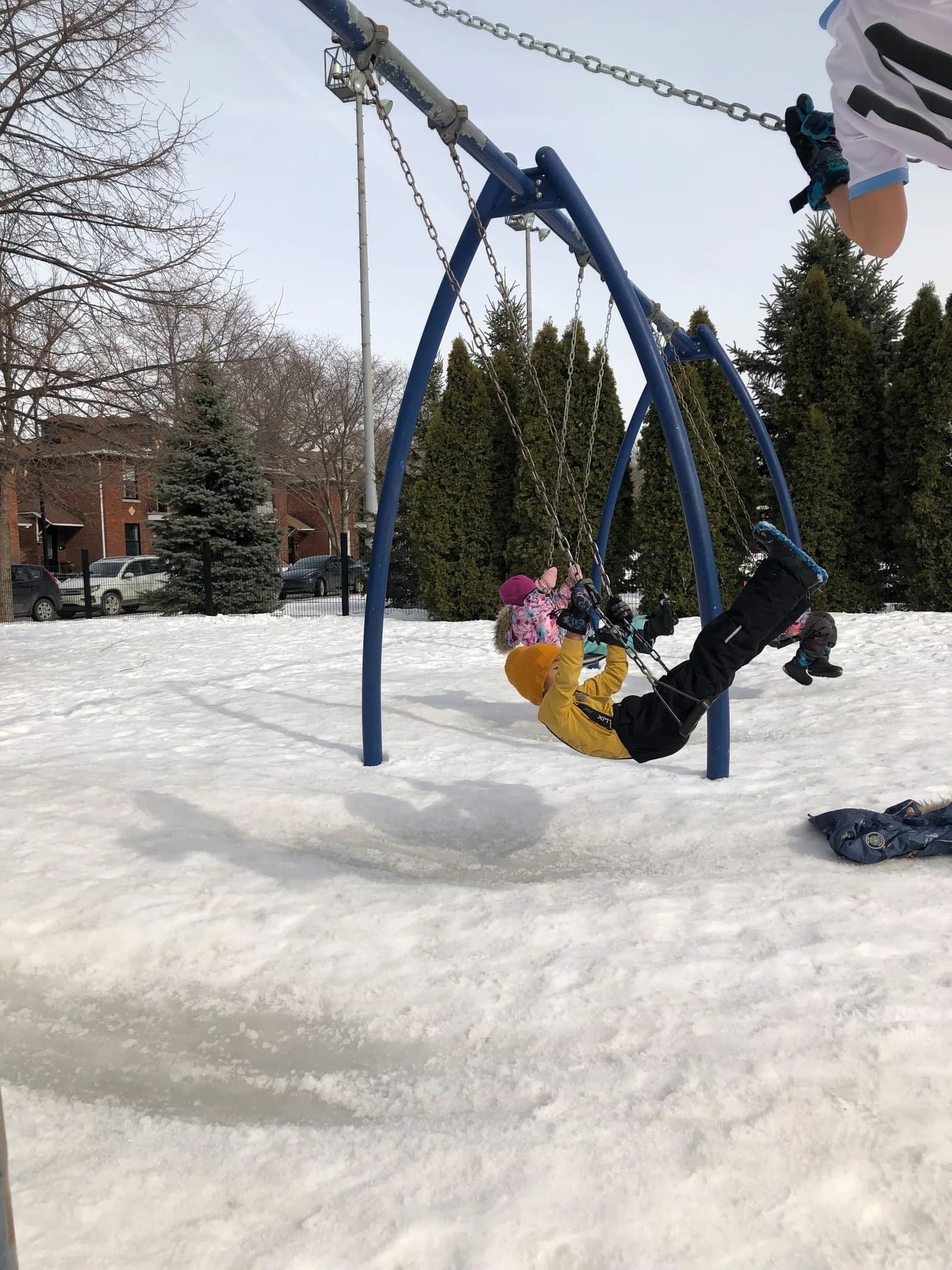 Laurus March Break campers playing on swings in a snowy playground